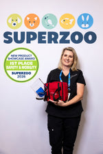 A veterinarian proudly holds a red pet first aid kit and a SuperZoo 2026 First Place Safety & Mobility award in front of a SuperZoo step-and-repeat backdrop.