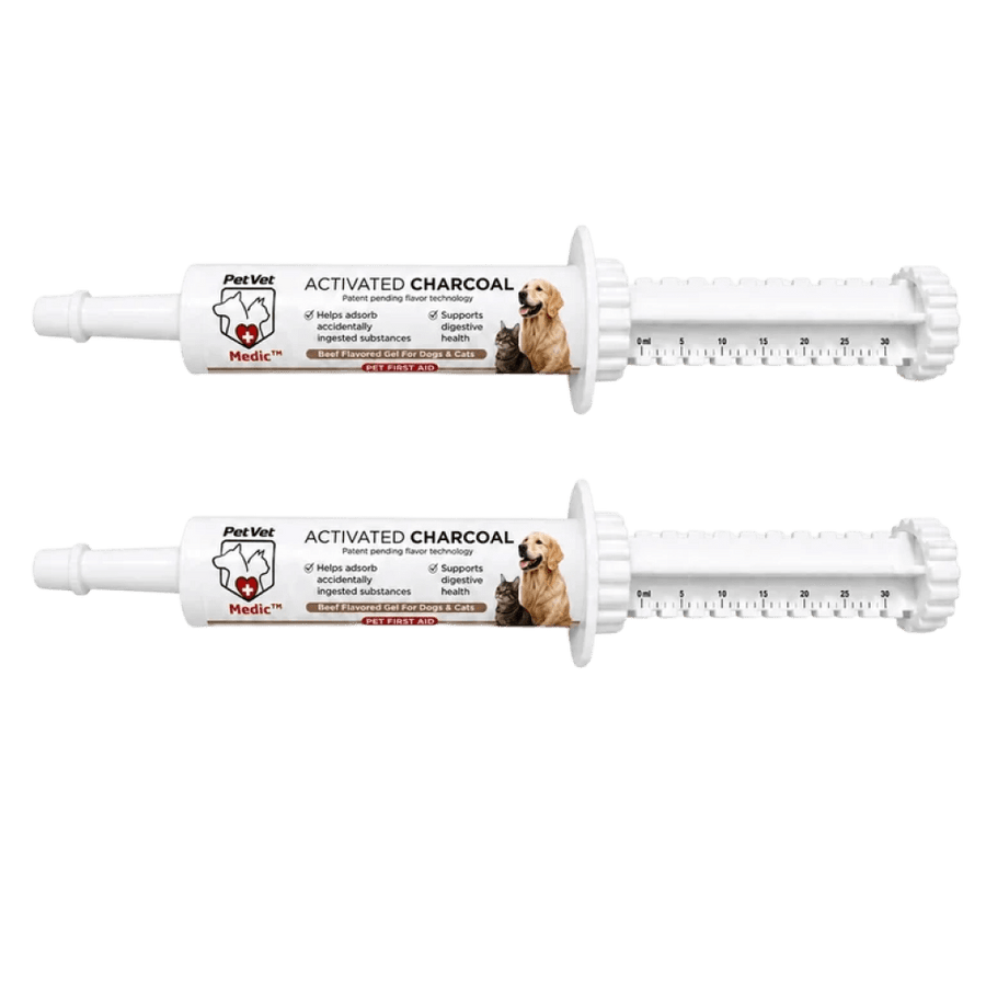 Two white PetVet activated charcoal syringes for dogs and cats lie horizontally against a white background.